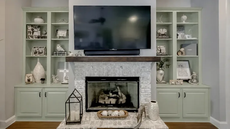 Paint Guru render — built-in bookcases and cabinets around the fireplace recolored to a light sage green