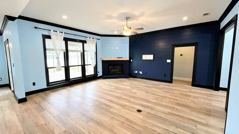 Paint Guru render — living room in Misty with a Naval accent wall, Tricorn Black trim and fireplace brick